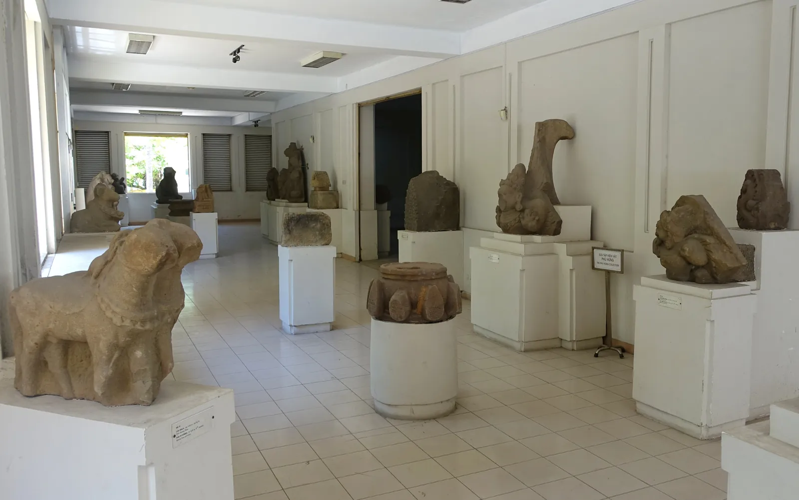 Utstillingssal med eldgamle Cham-skulpturer i stein på hvite sokler i Cham-skulpturmuseet i Da Nang