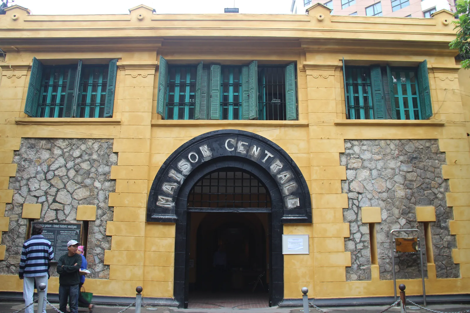 Gul inngangsfasade med buet port og påskriften Maison Centrale ved Hoa Lo-fengselet i Hanoi
