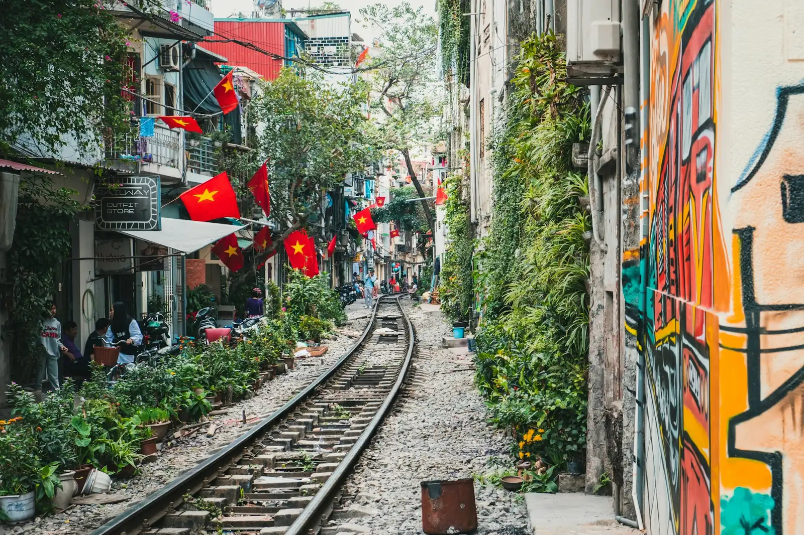 Jernbanesporet i en smal gate i Hanoi med vietnamesiske flagg og veggmaleri