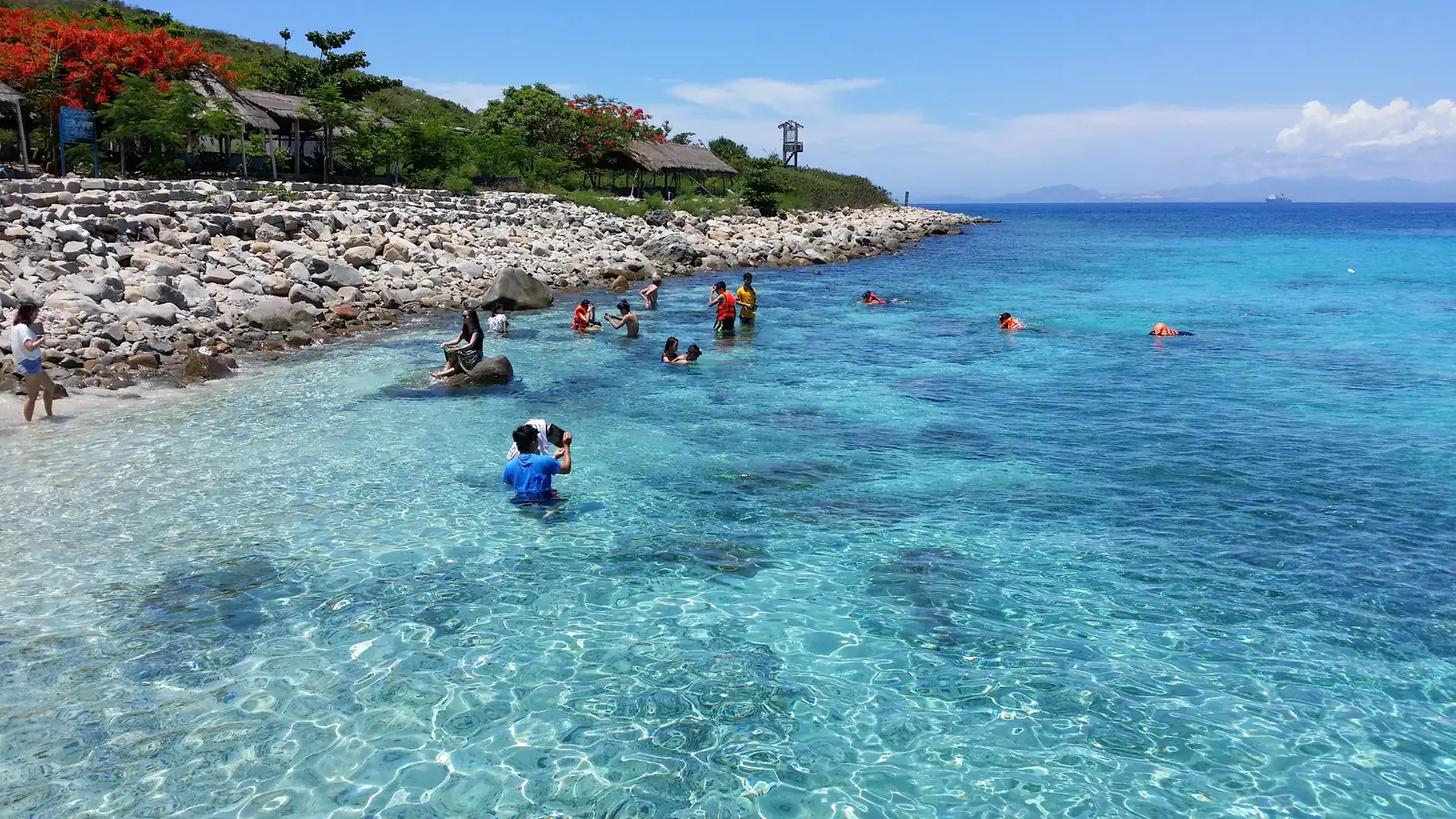 Turkis, klart vann og snorklere ved steinstranden på Hon Mun-øya utenfor Nha Trang