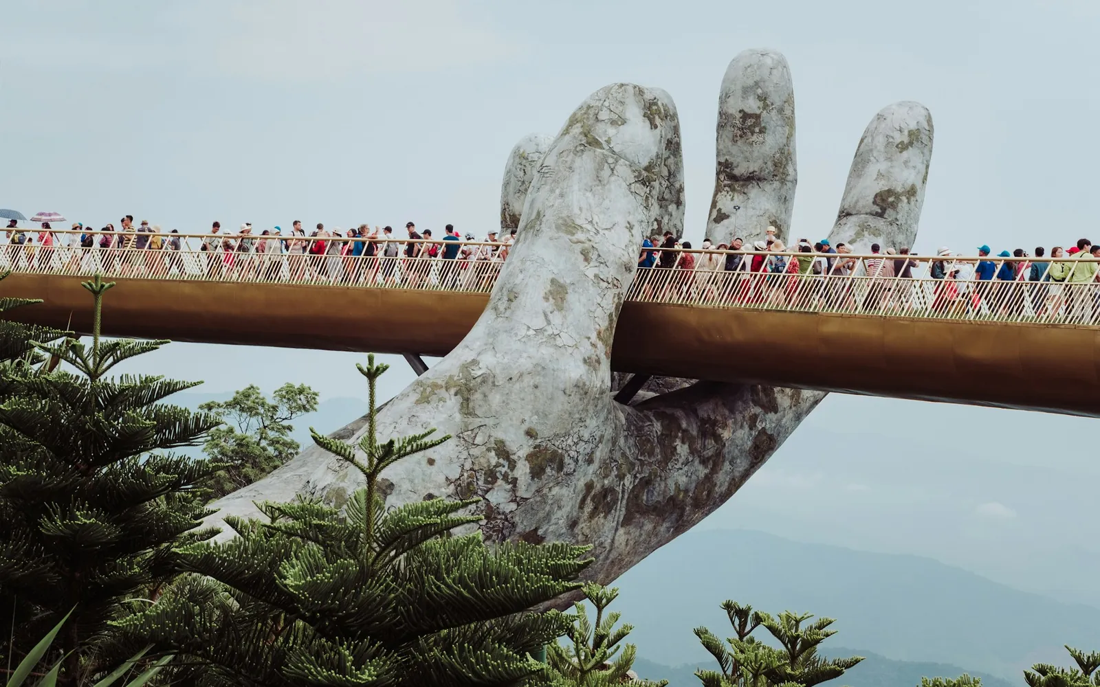 Turister på Golden Bridge på Ba Na Hills, båret av en stor steinhånd over fjellene