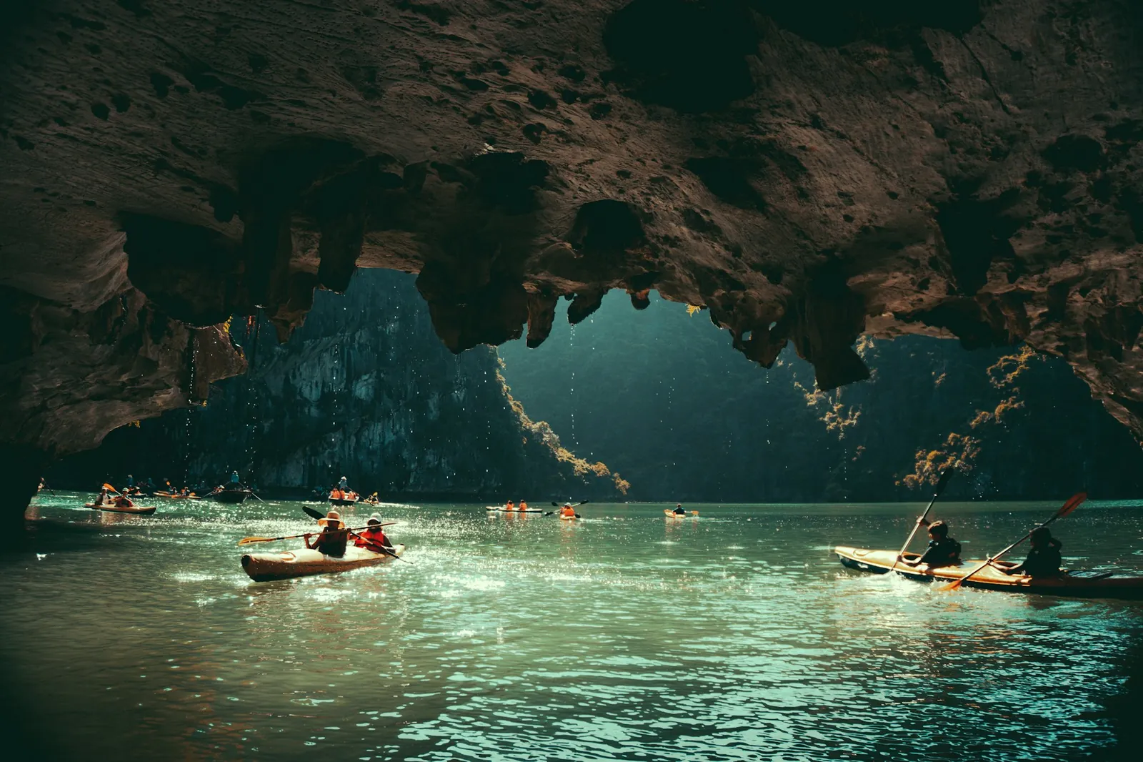 Kajakkpadlere i et lyst basseng under en grotte i Ha Long-bukta omgitt av kalksteinsklipper