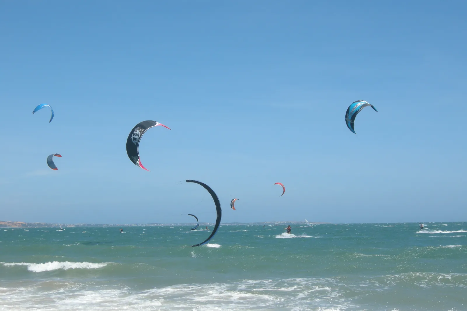 Mange kitesurfere og drager over det blå havet ved Mui Ne-stranden