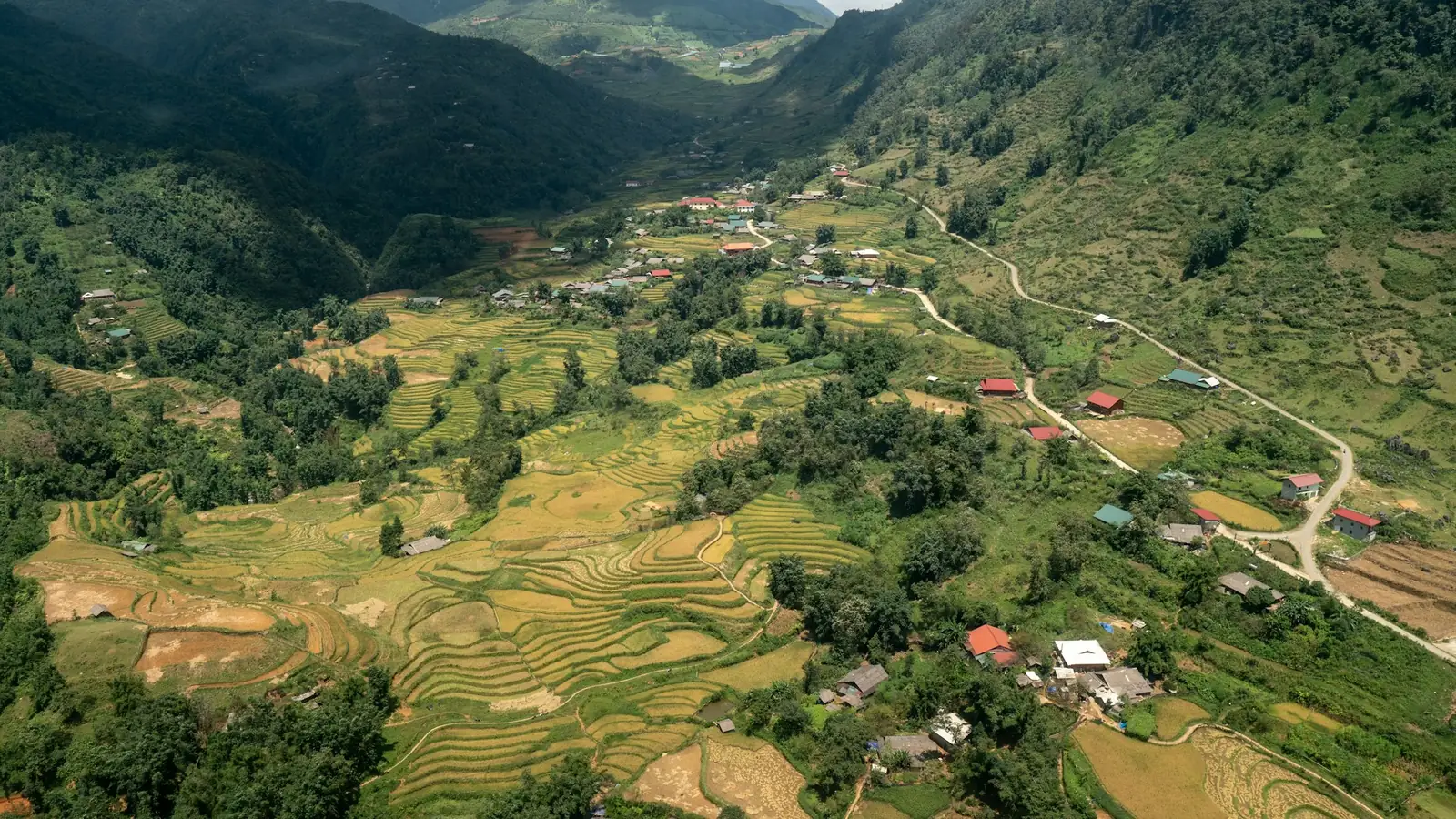 Landsby og gyllne risterrasser i en fjelldal ved Sapa sett ovenfra