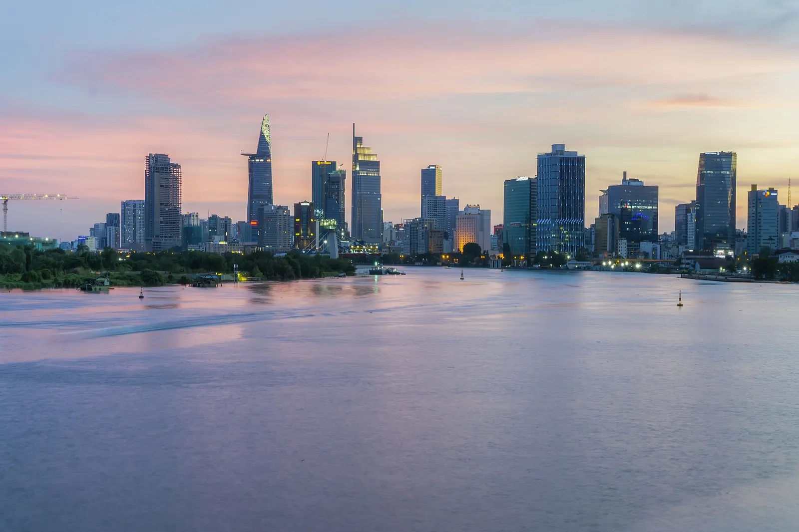 Skyline med forretningsbygg over Saigon-elva i Ho Chi Minh-byen ved solnedgang