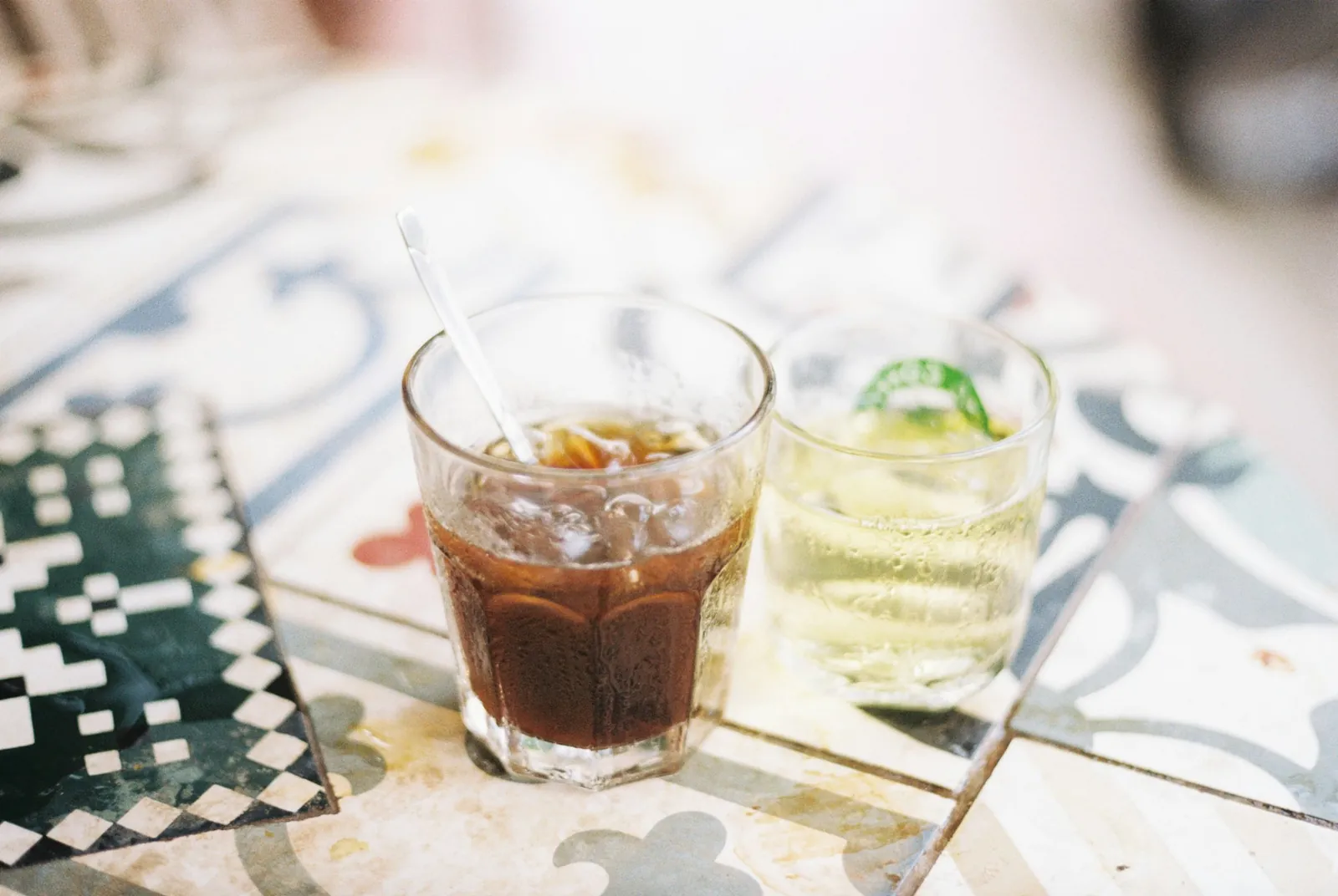 Iskaffe og lime-drikk i glass på kafébord med mønstrede fliser