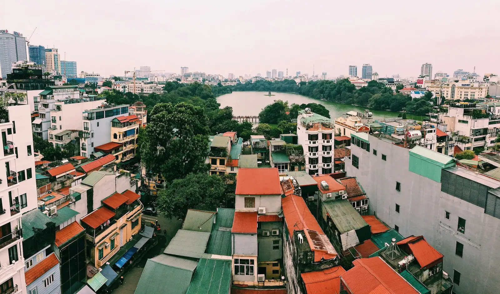 Hustak og smale bygårder i Hanoi med en innsjø i bakgrunnen