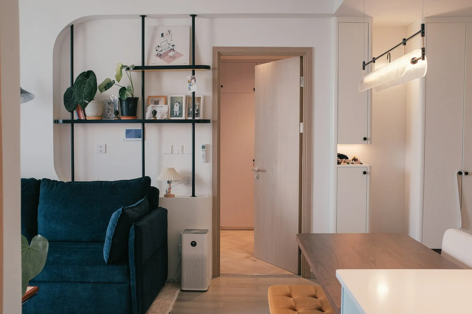 Lys moderne leilighet med blå sofa, hylle og åpen dør