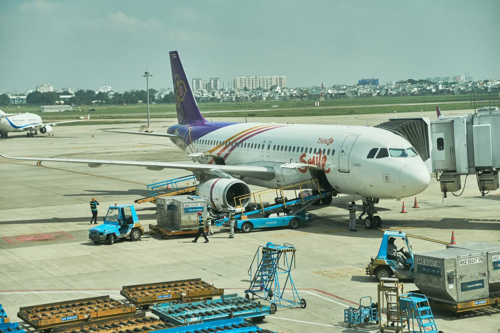 Thai Smile-fly ved gate på Tan Son Nhat lufthavn i Ho Chi Minh-byen med bagasjevogner på flyplassen