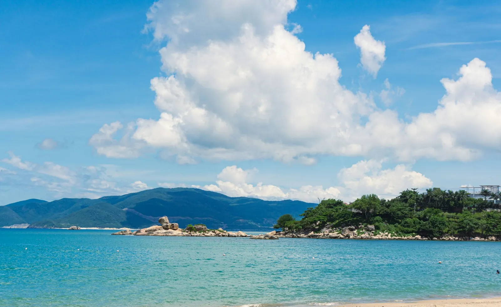 Blått hav, sky og en grønn øykyst ved Nha Trang en sommerdag