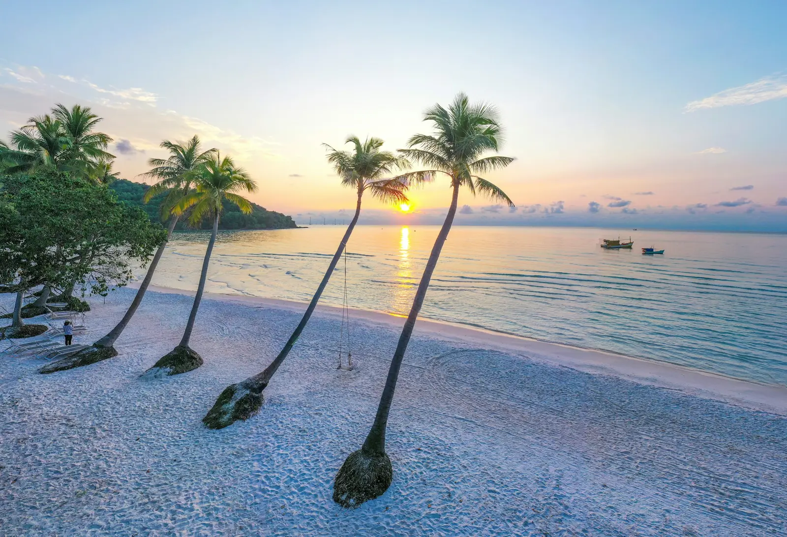 Skråstilte palmer over hvit sandstrand ved solnedgang på Phu Quoc