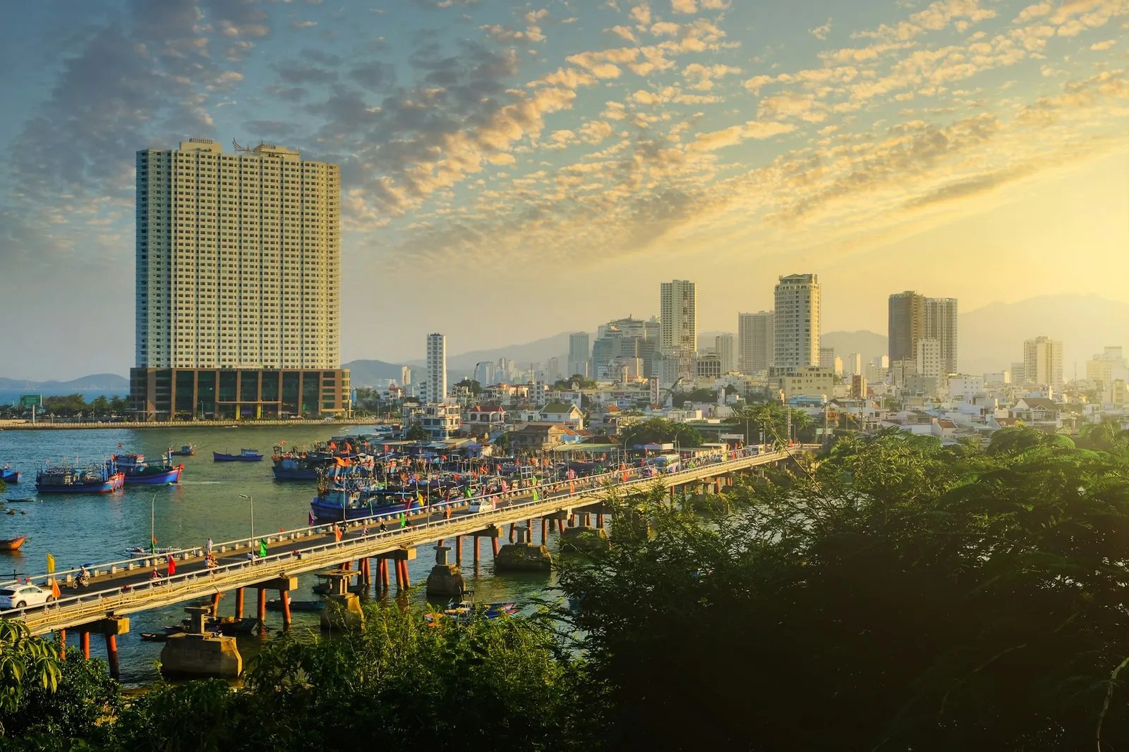 Bro over Cai-elva i Nha Trang ved solnedgang med hotell og byen i bakgrunnen