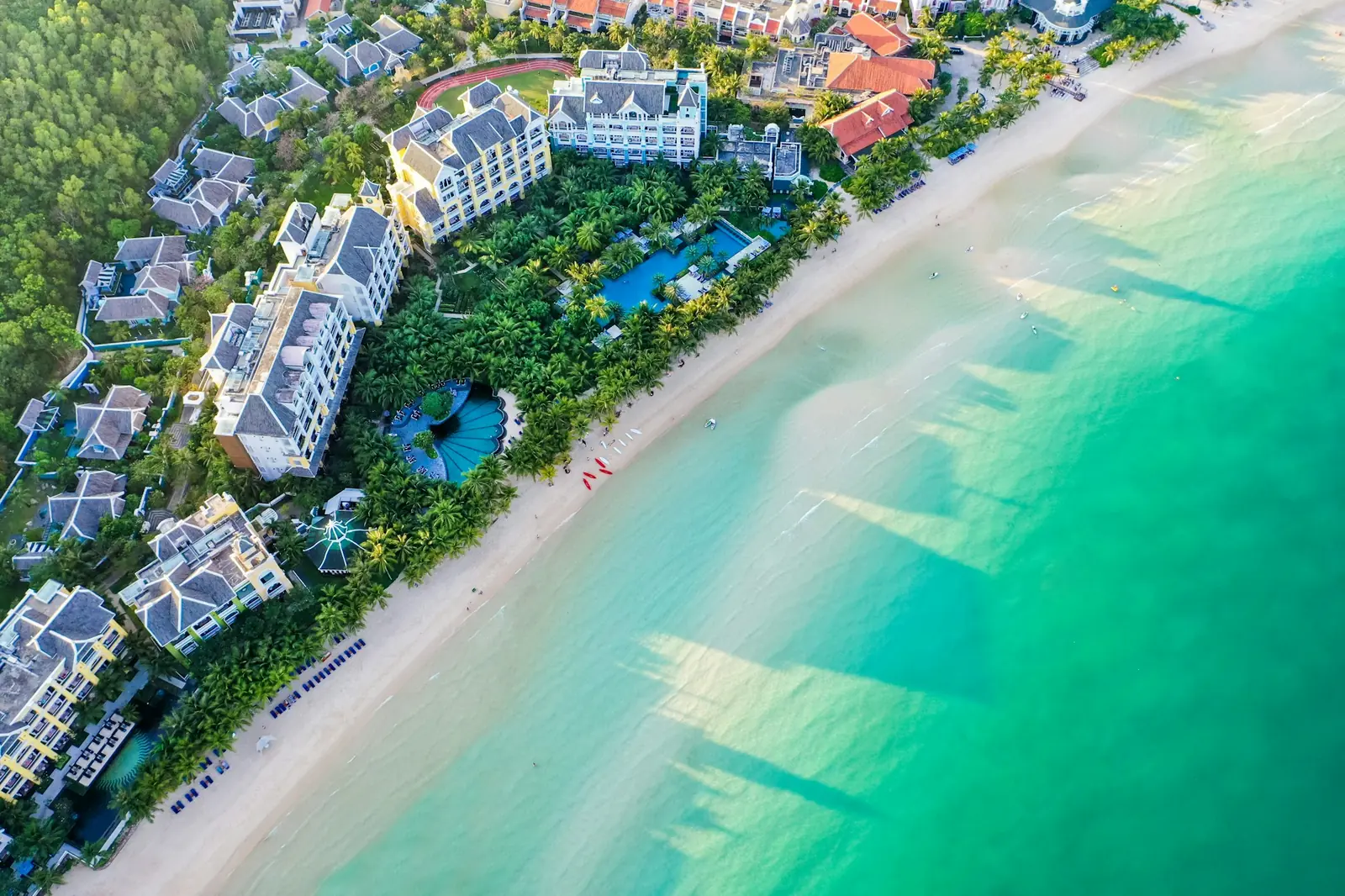 Flyfoto av resort langs en lang hvit sandstrand på Phu Quoc med turkist hav