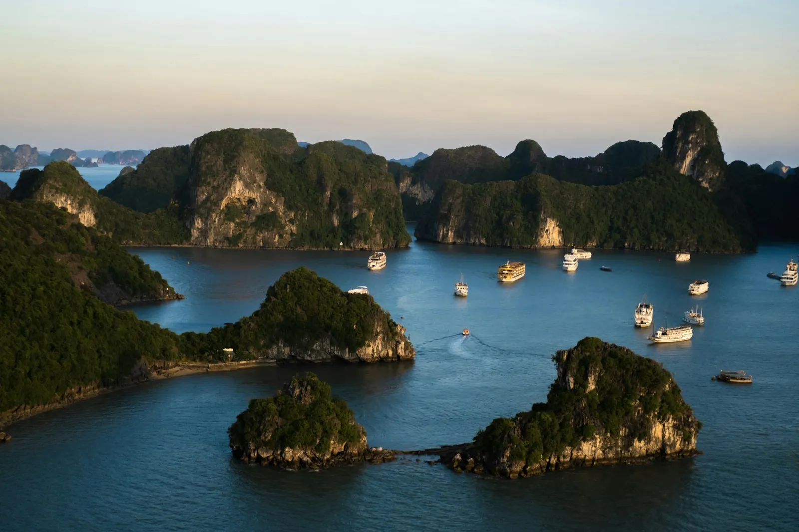 Kalksteinsøyer og båter i en rolig bukt i Ha Long-området i morgenlys