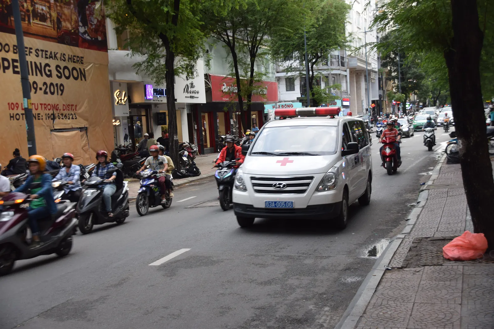 Hvit ambulanse med rødt kors i bytrafikk med scootere i Ho Chi Minh-byen