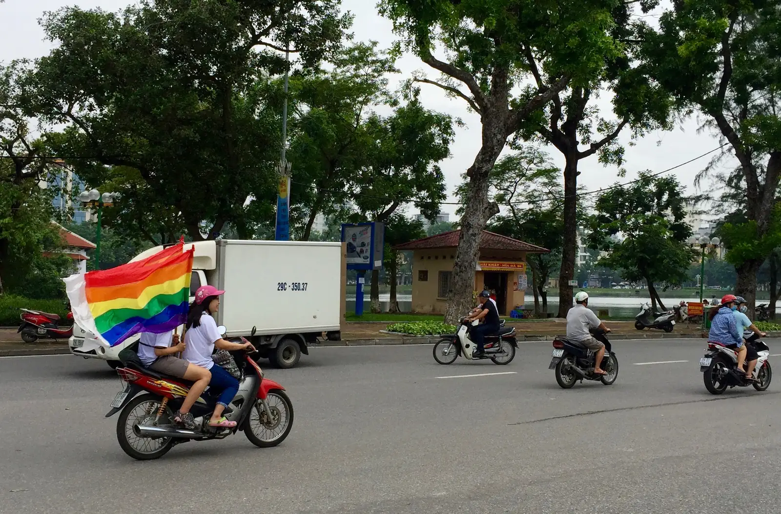 Scooter med regnbueflagg under Viet Pride i Hanoi i 2016, med trær og trafikk langs gata
