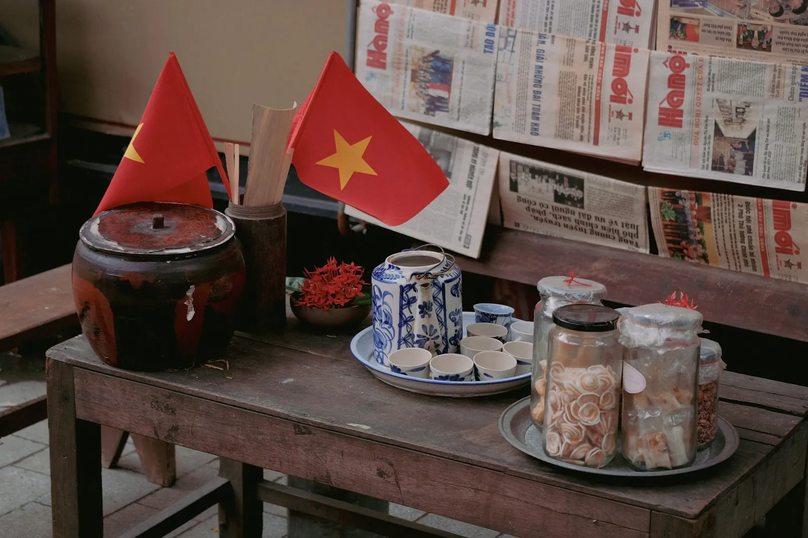 Små vietnamesiske flagg på et bord med aviser, krukker og porselen