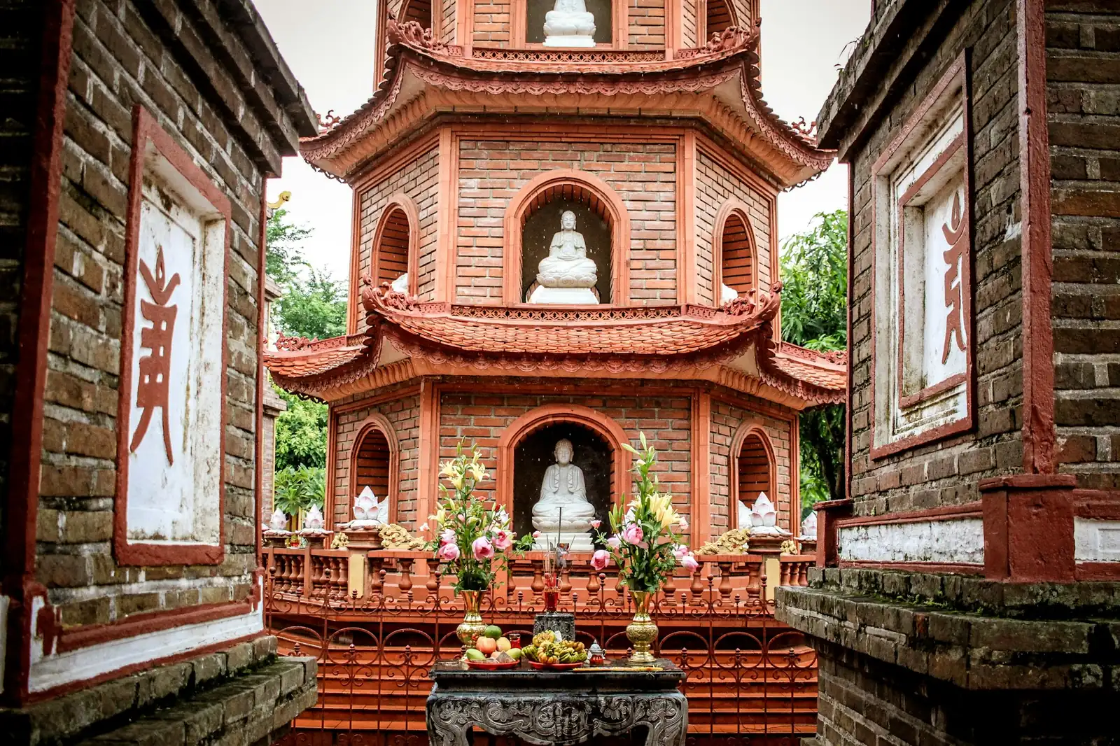 Mursteinspagode med buddhastatuer i nisjene og blomster- og fruktofringer