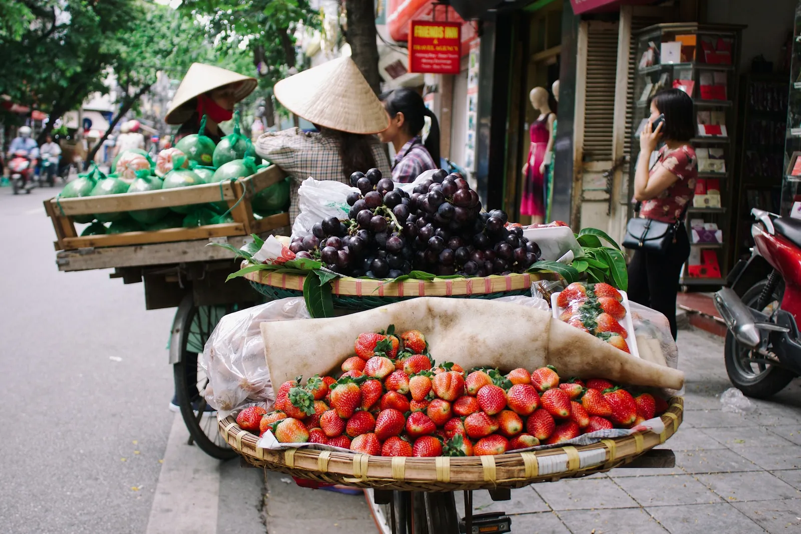 Sykkel lastet med jordbær, druer og pomelo hos en fruktselger i Hanoi