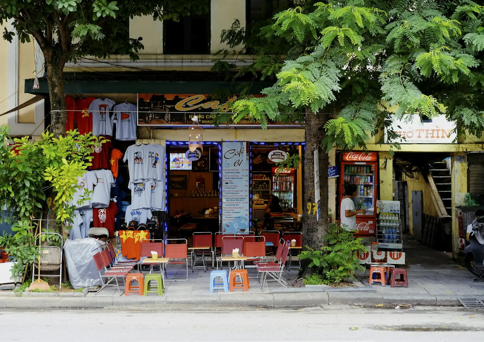 Suvenirbutikk med T-skjorter og kafé langs en gate i Hanoi