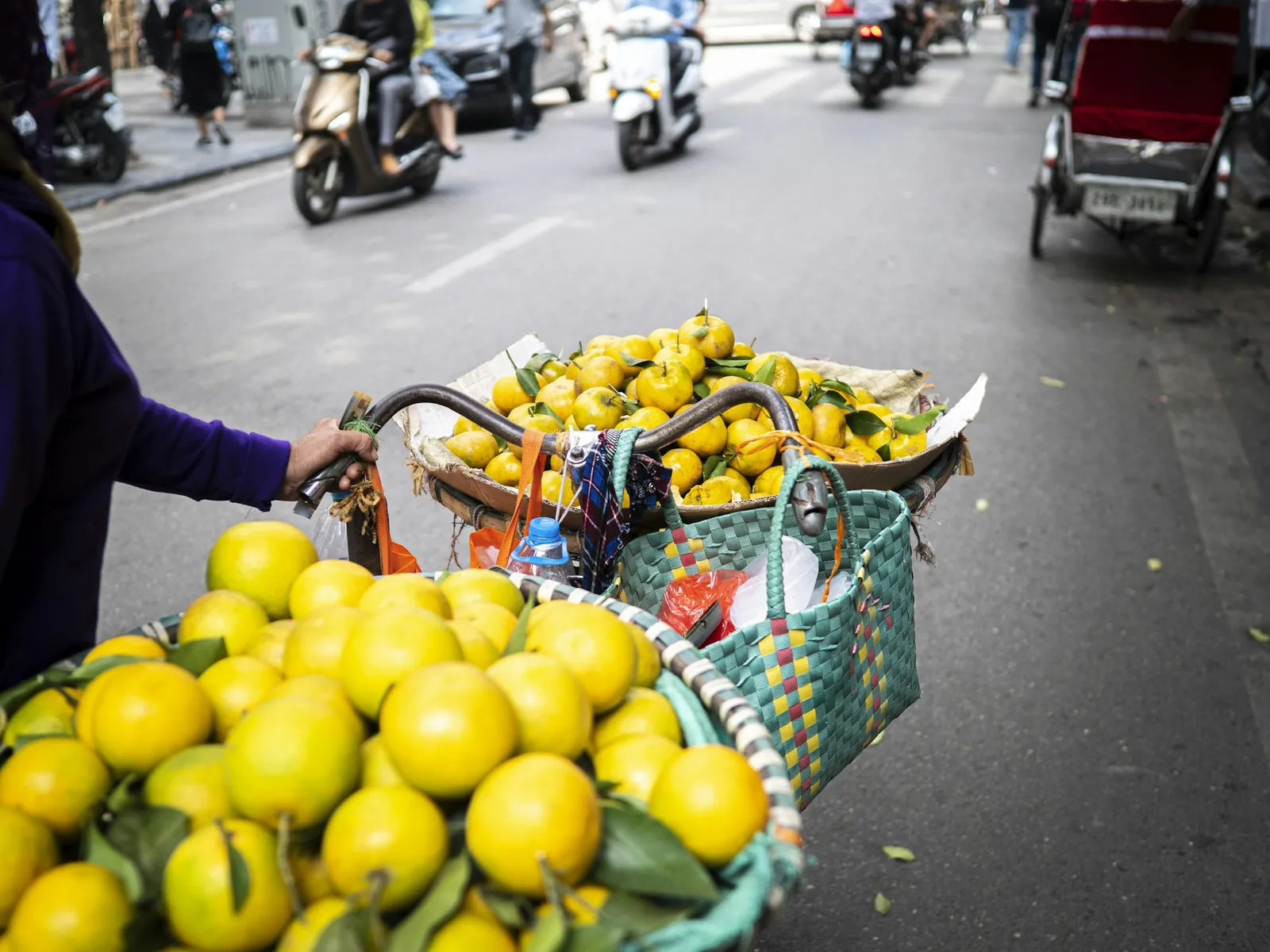 Sykkel med korger full av gule sitrusfrukter i en gate i Hanoi