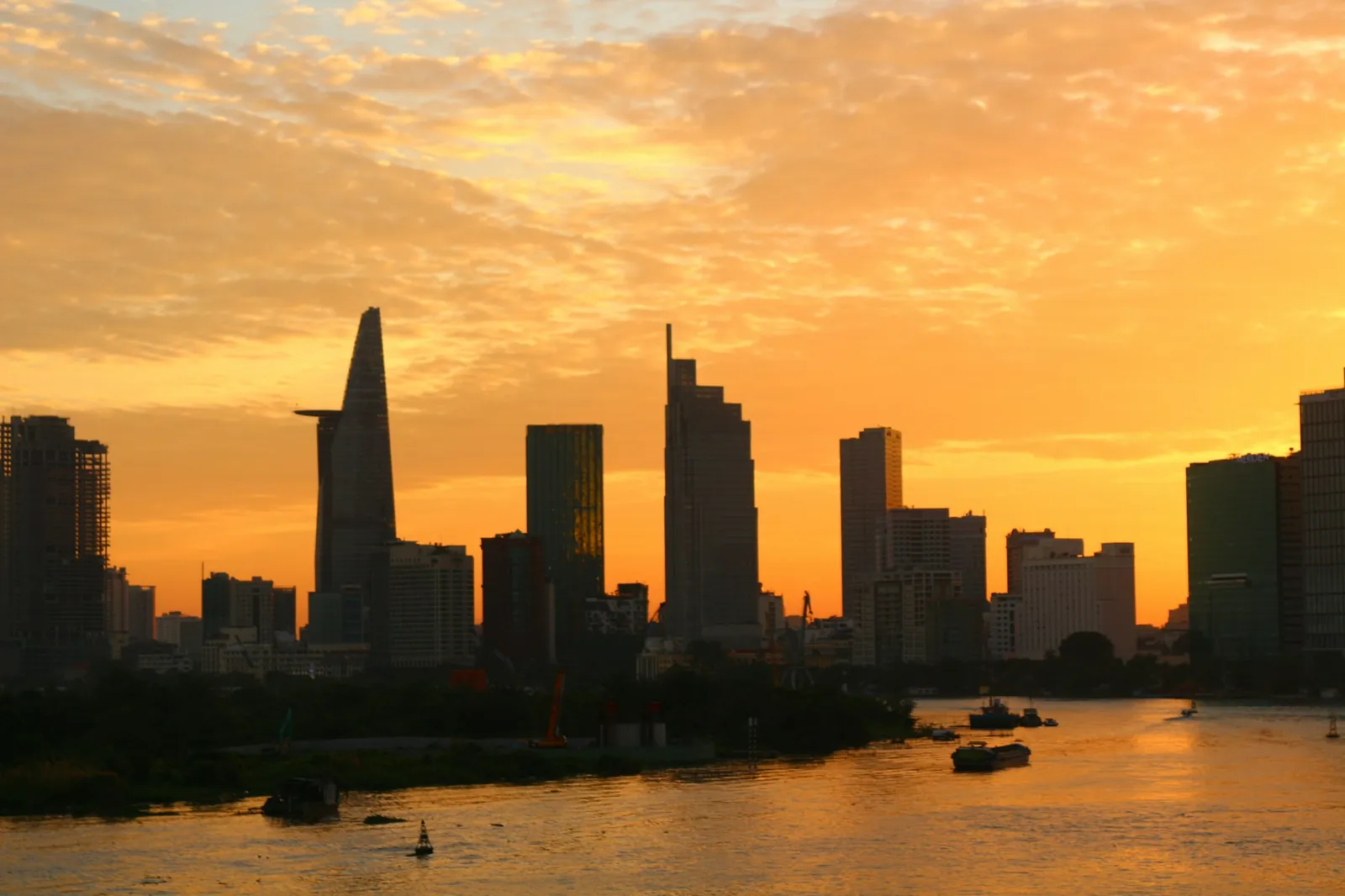 Silhuett av skyskrapere i Ho Chi Minh-byen mot oransje solnedgang