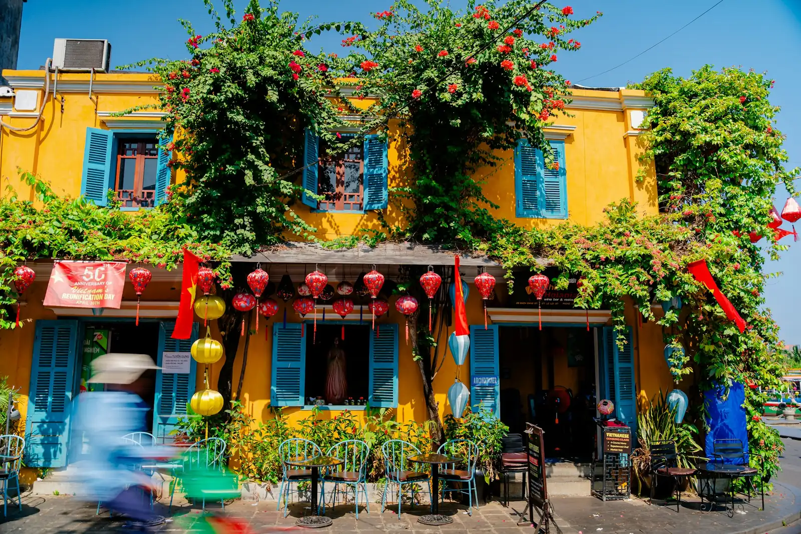 Gul husfasade med blomster og røde lykter i gamlebyen i Hoi An