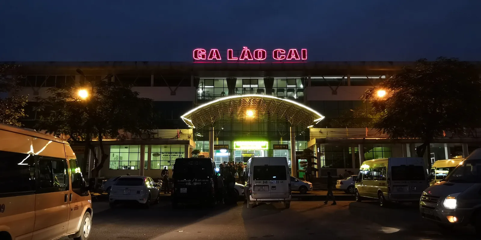 Lao Cai jernbanestasjon opplyst om kvelden med minibusser utenfor