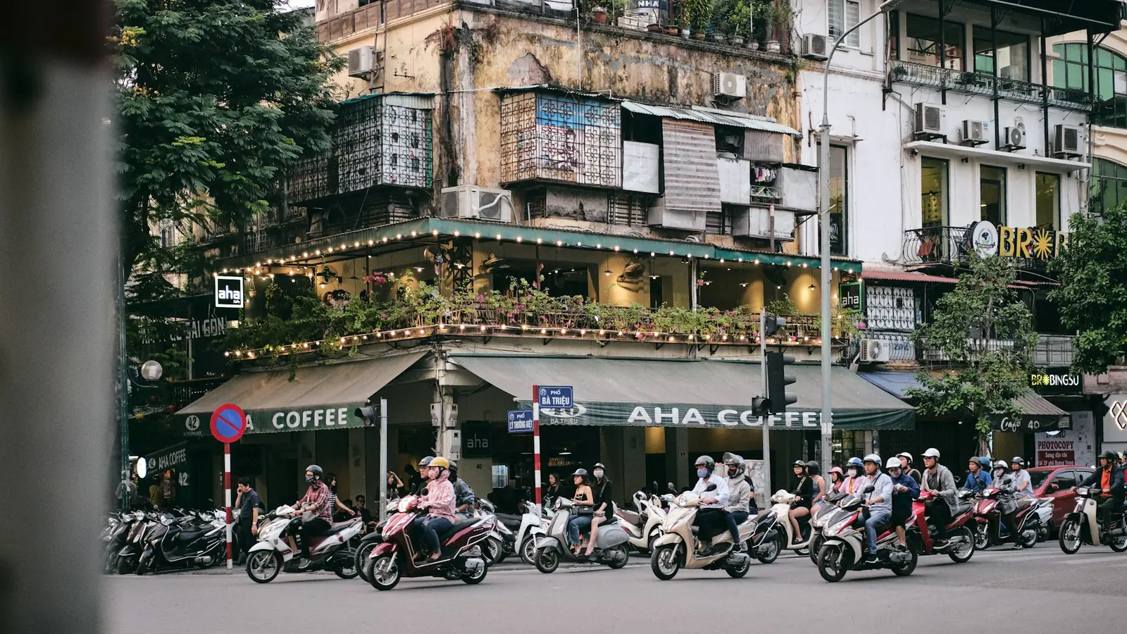 Scootere venter i veikryss foran en kafé i gamlebyen i Hanoi