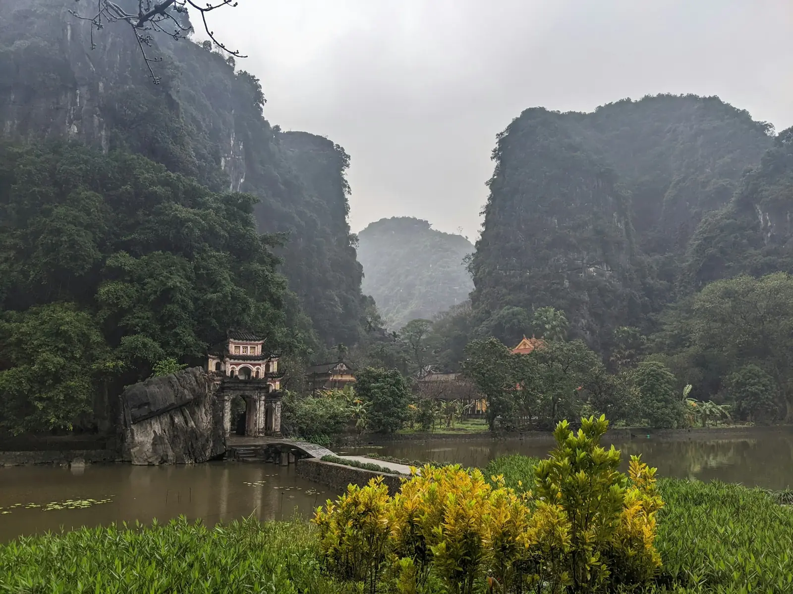 Grå og disig dag ved Bich Dong-pagoden i Ninh Binh med kalksteinsfjell og dam